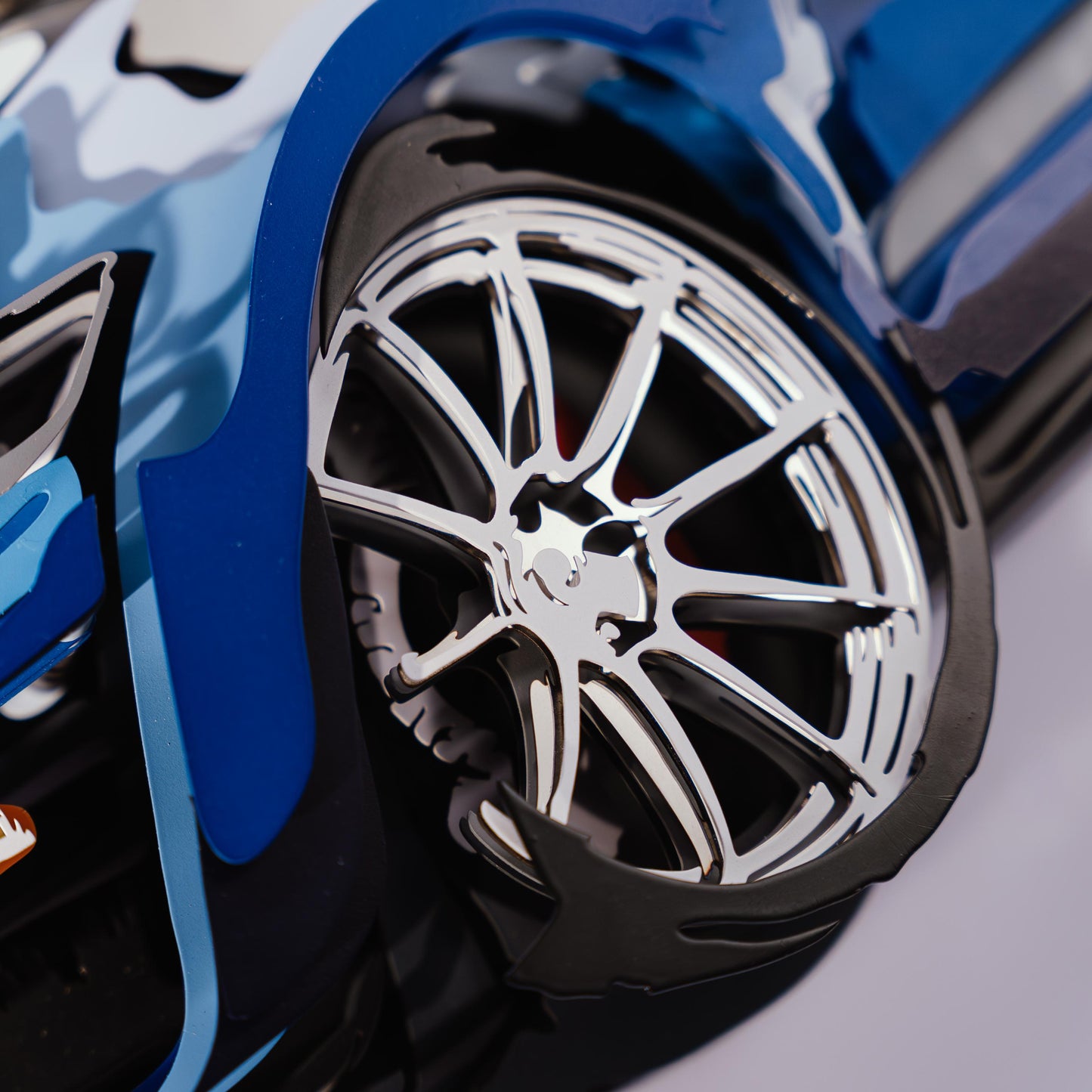 Close-up of a blue car model wheel with a shiny rim on a blurred background