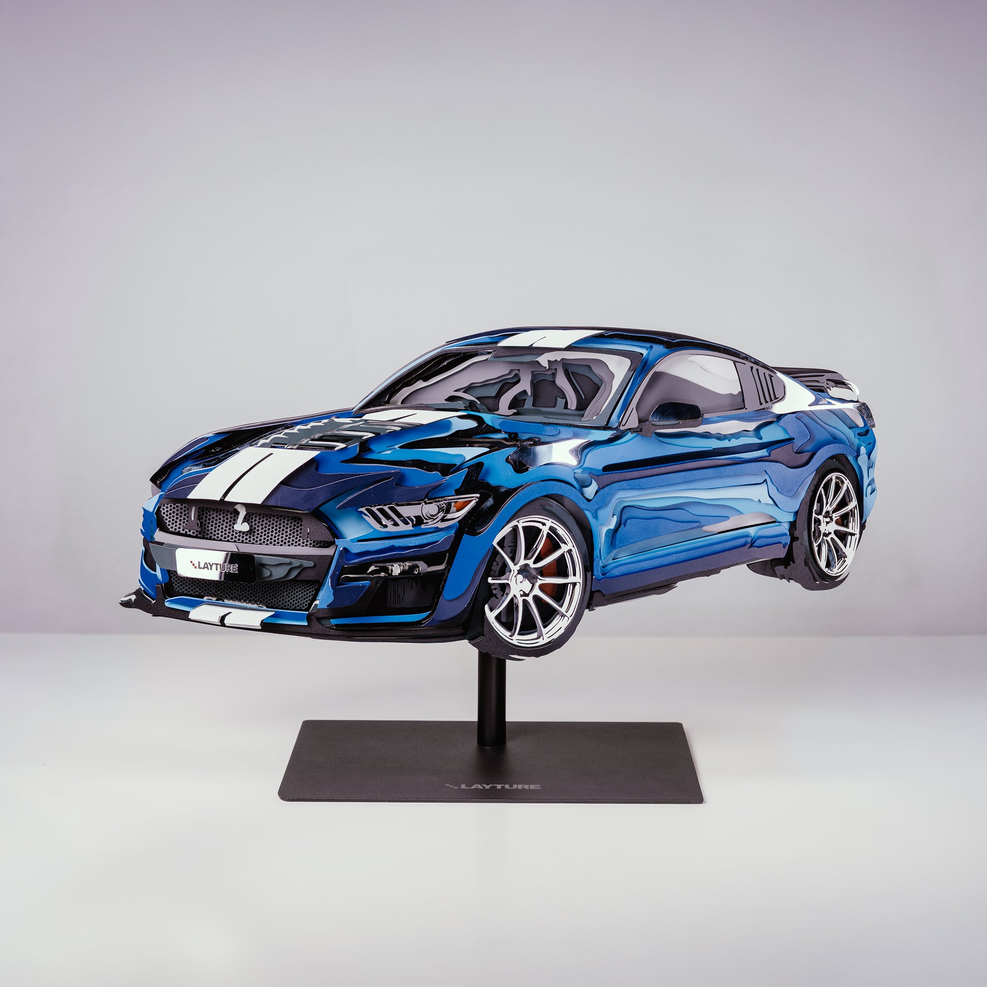 Blue sports car model on a stand against a gray background