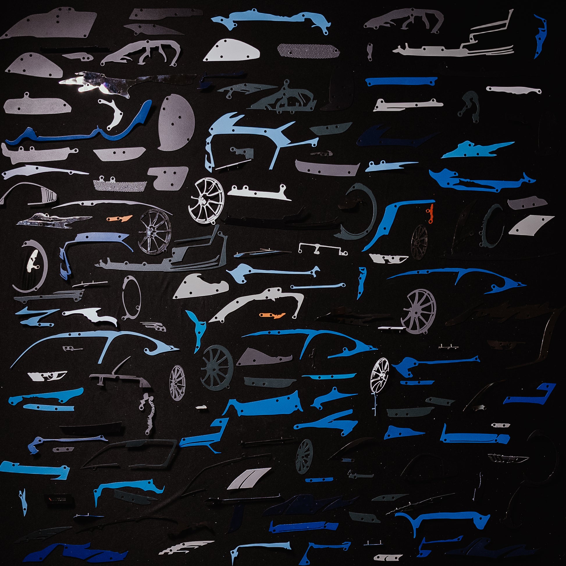 Collection of blue car model panels and parts on a black background