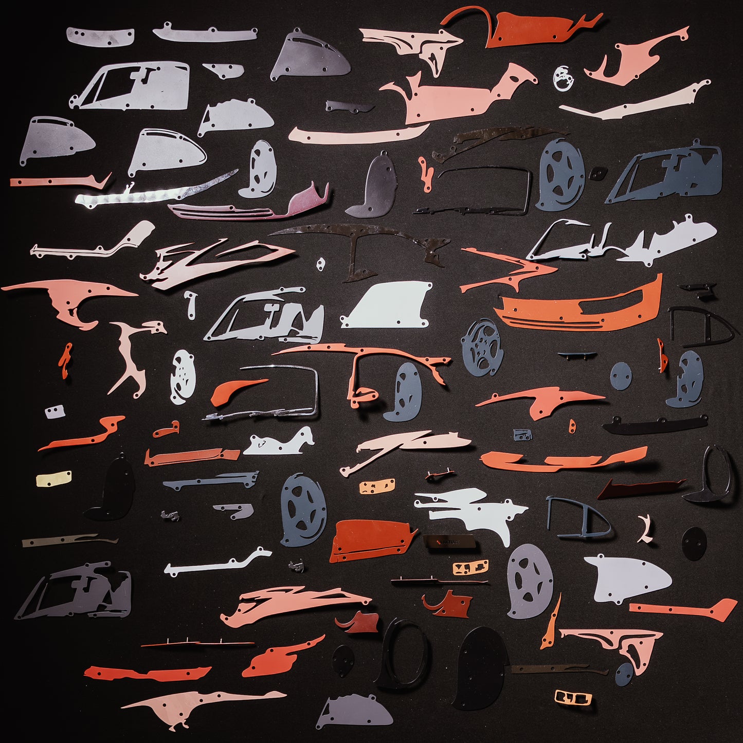 Collection of red car model panels and parts on a black background
