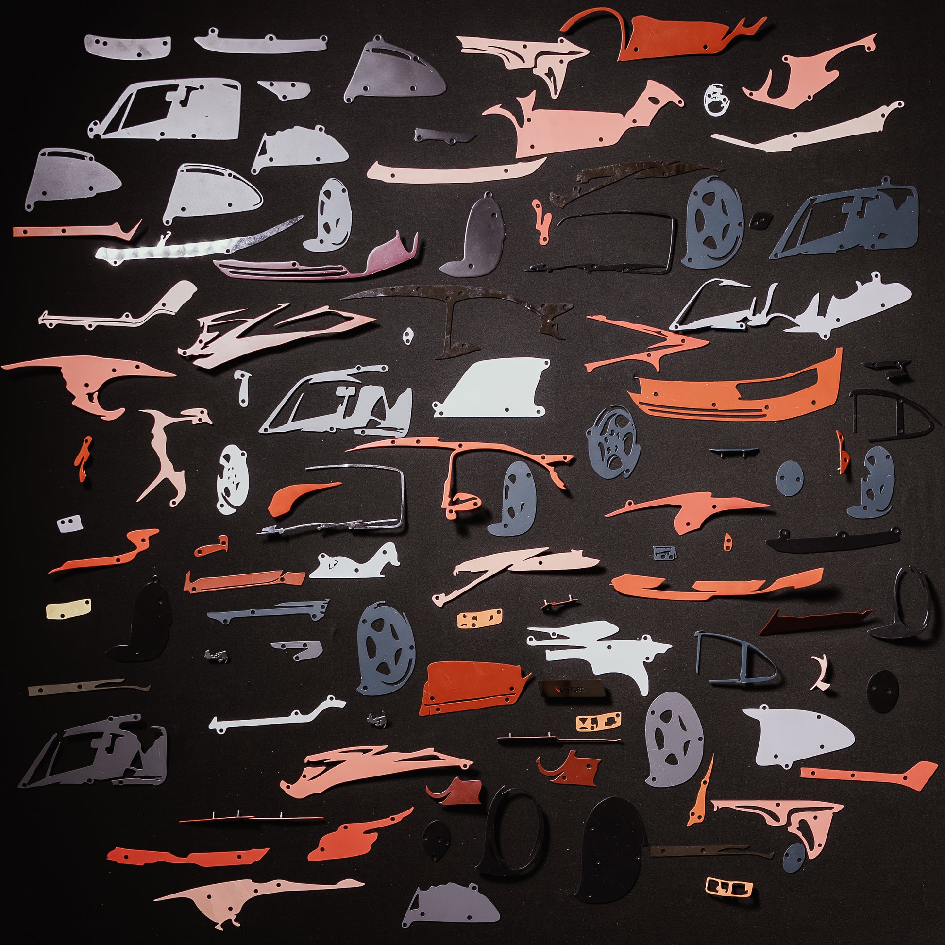 Collection of red car model panels and parts on a black background