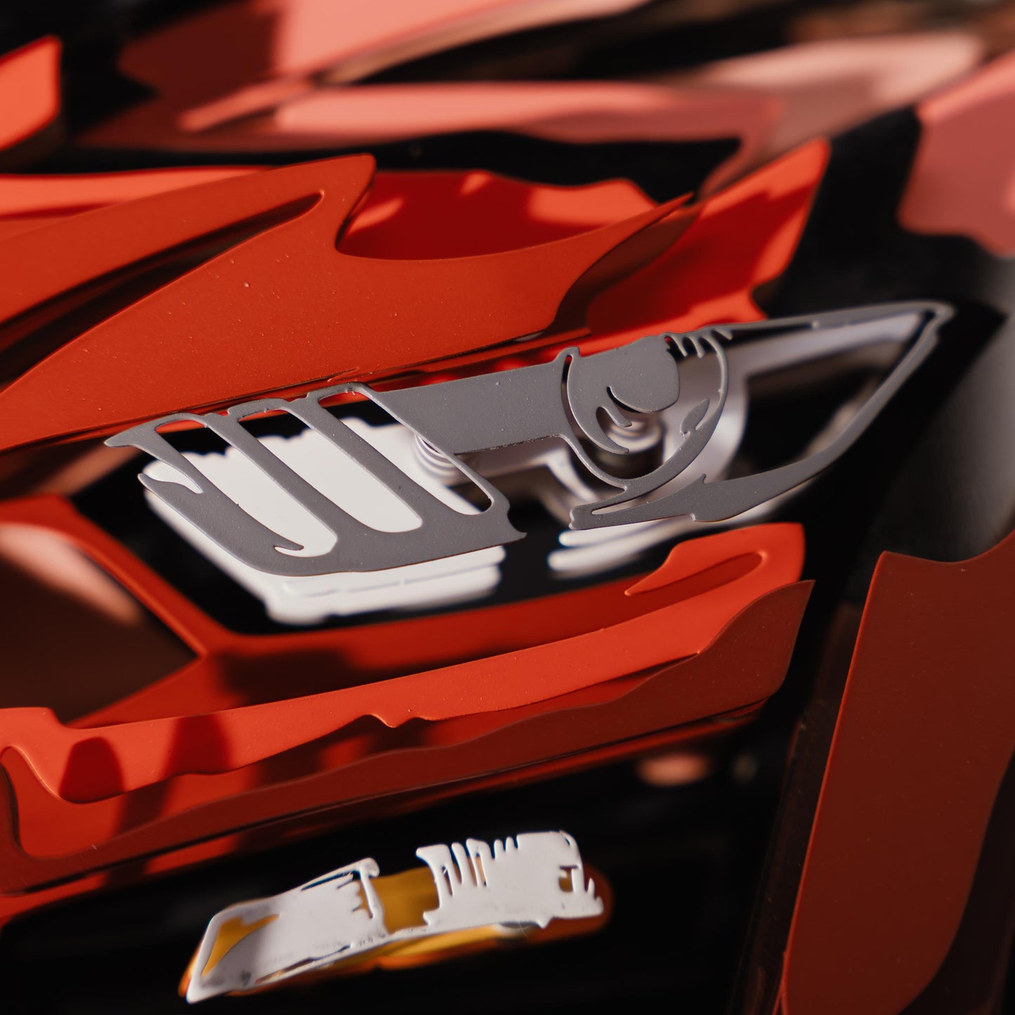 Close-up of a red and black car model with a prominent logo on the grille.