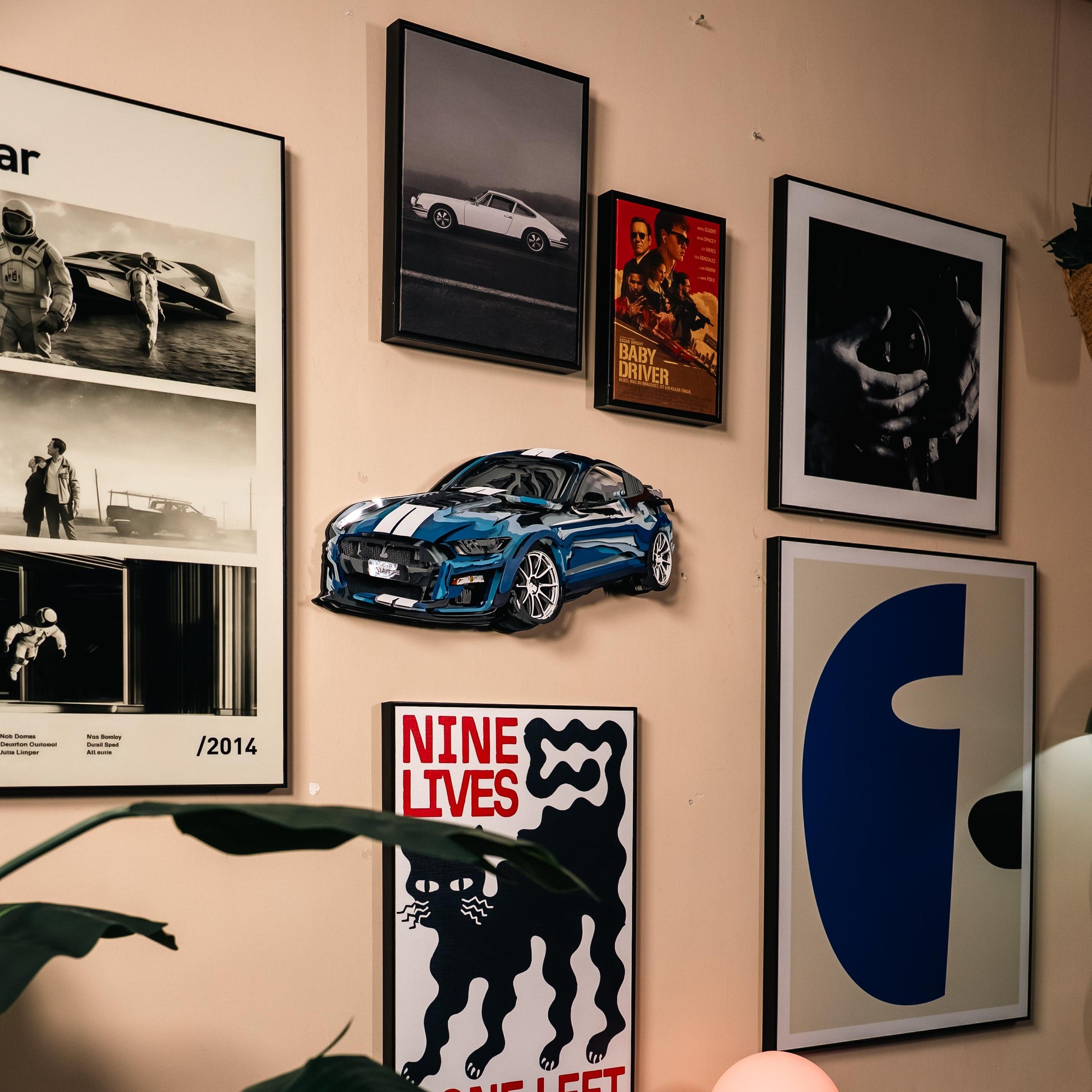 Wall with framed pictures and a blue 3D car model