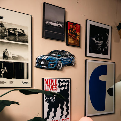 Wall with framed pictures and a blue 3D car model