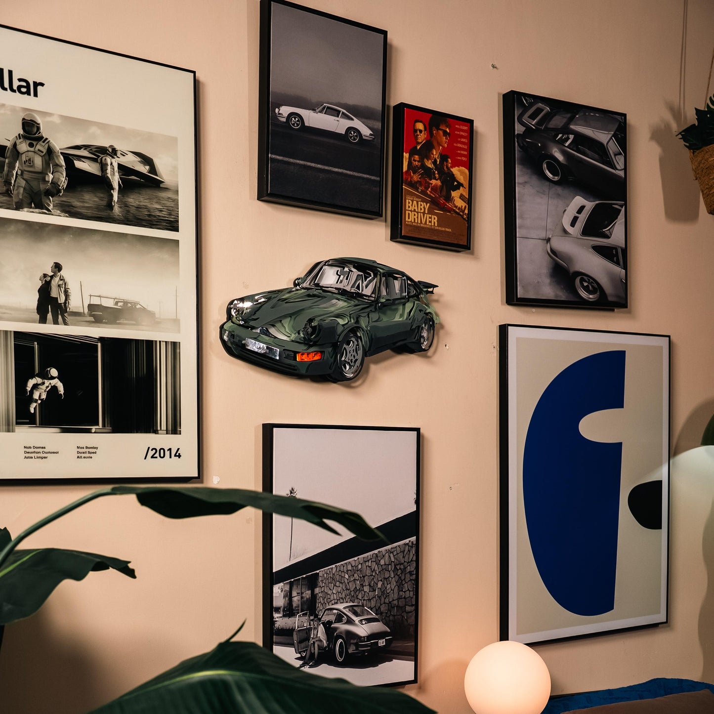 Wall with framed pictures and a model car of a green sports car.