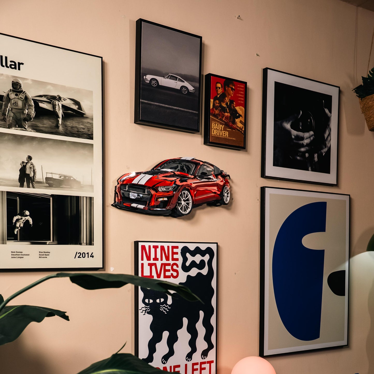 Wall with framed pictures and a red car model on a beige wall